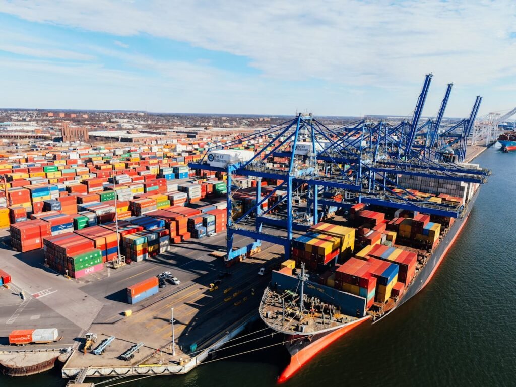 From above of cargo ship moored in port while unloading colorful containers in sunny day